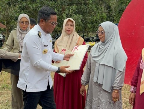 Bupati Pelalawan H. Zukri SM menyerahkan sertifikat redistribusi tanah kepada warga Desa Dundangan tahun 2025