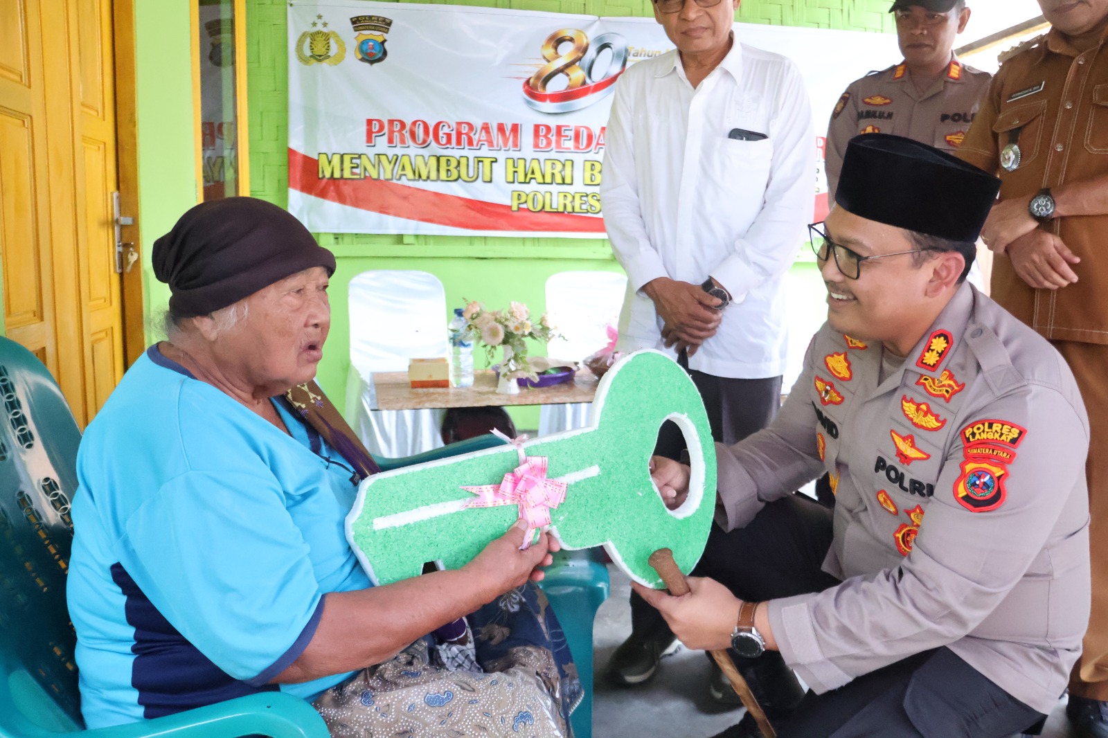 Momen Ibu Ginah menyematkan sarung ke leher Kapolres Langkat AKBP David Triyo Prasojo saat penyerahan bedah rumah