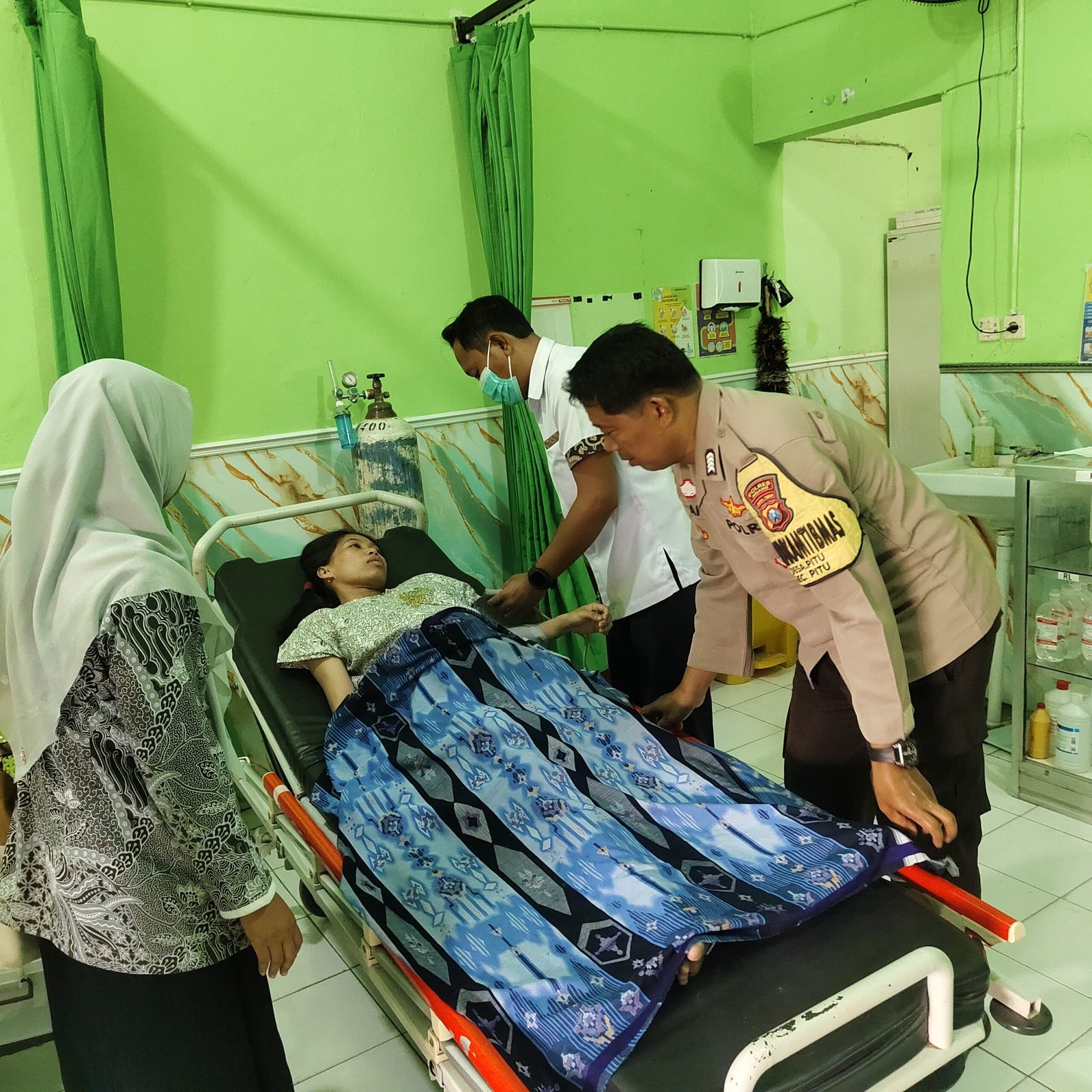 Anggota Bhabinkamtibmas Polsek Pitu Bripka Gianto membantu menuntun ibu hamil Devi Rahayu menuju UGD Puskesmas Pitu Ngawi.