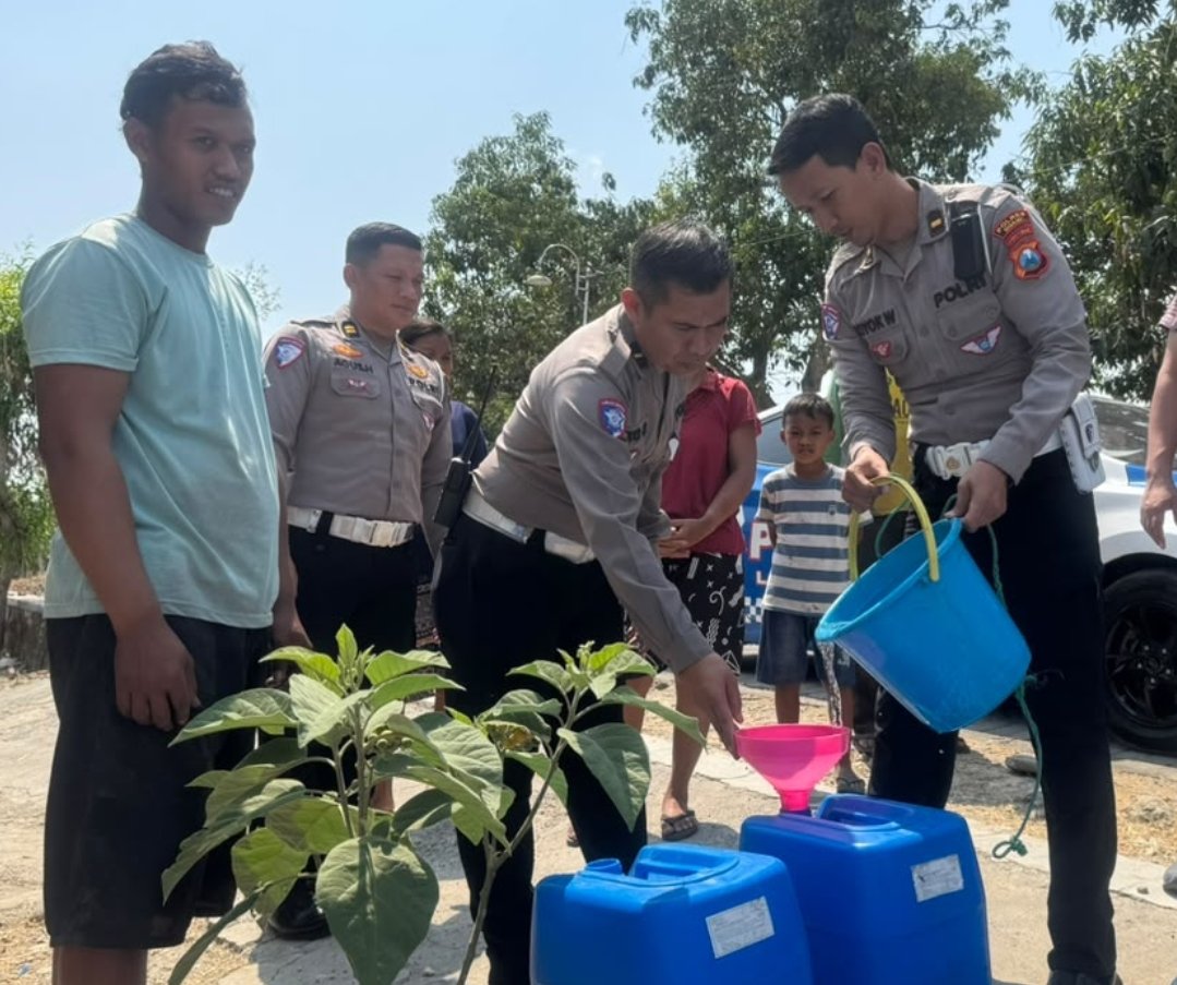 Kasatlantas Polres Ngawi AKP Moh. Imam Reza mengisikan air bersih ke wadah milik warga terdampak kekeringan di Kecamatan Bringin.