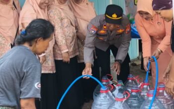 Petugas Polsek Pitu bersama pengurus DWP mengisikan air bersih ke wadah penampungan milik warga di Desa Cantel Pitu Ngawi.
