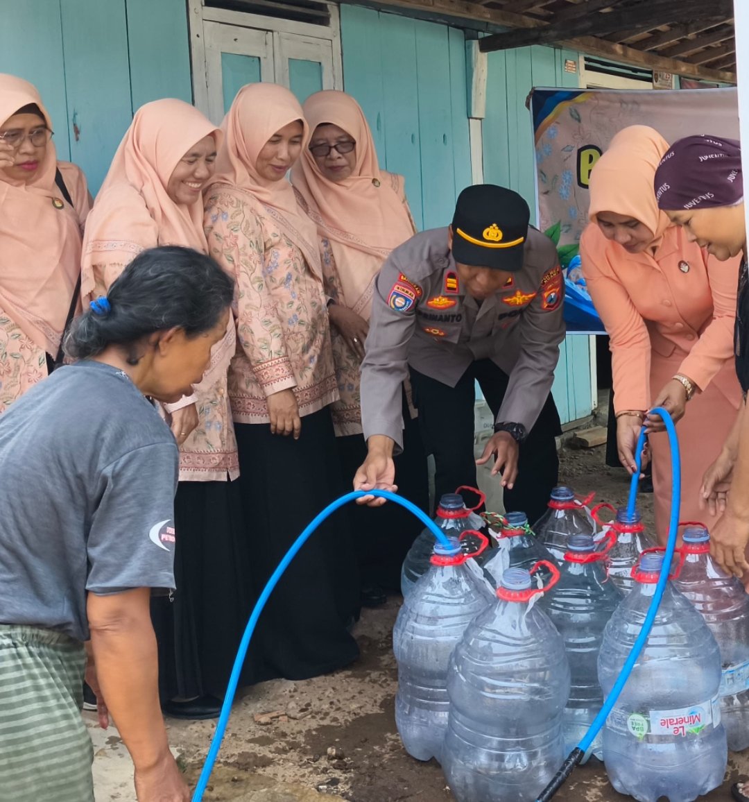 Petugas Polsek Pitu bersama pengurus DWP mengisikan air bersih ke wadah penampungan milik warga di Desa Cantel Pitu Ngawi.